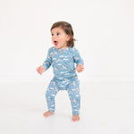 Child wearing a blue pajama with airplane pattern on a white background