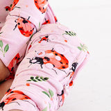 Baby wearing a pink floral onesie sitting on a white background