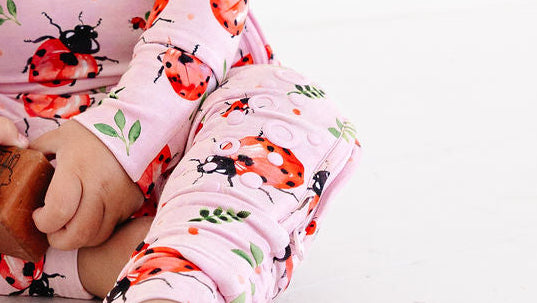 Baby wearing a pink floral onesie sitting on a white background