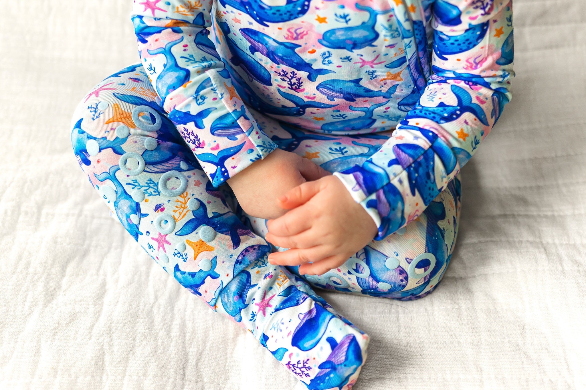 Kaizen Baby Ocean Slumber Knee-Grip Footie bamboo pajamas - Cropped seated baby, grip dots on legs clearly featured